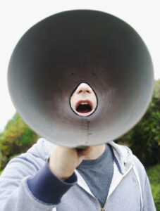 Unique brand voice: image of a young man yelling through a megaphone
