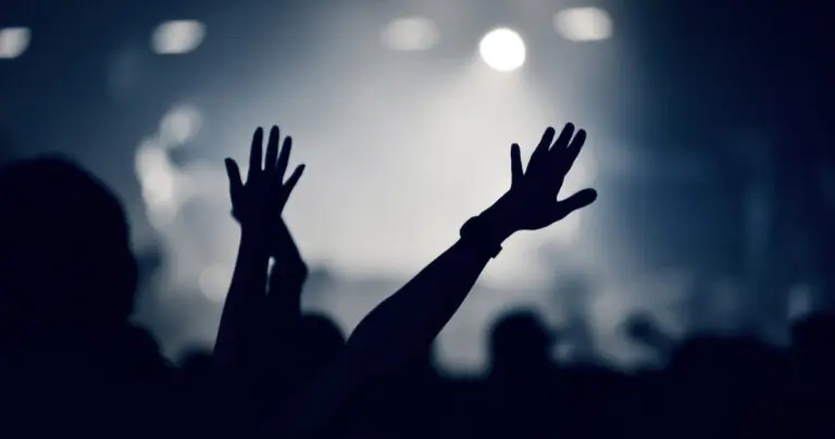 Crowd at a music concert, audience raising hands up, toned