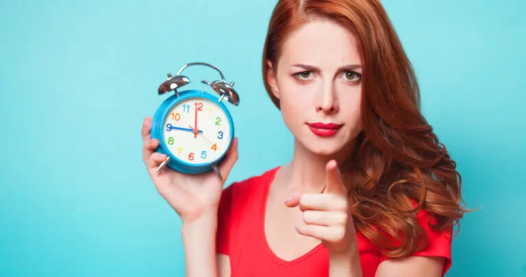redhead-girl-with-alarm-clock-on-blue-background-2022-01-13-01-18-07-utc